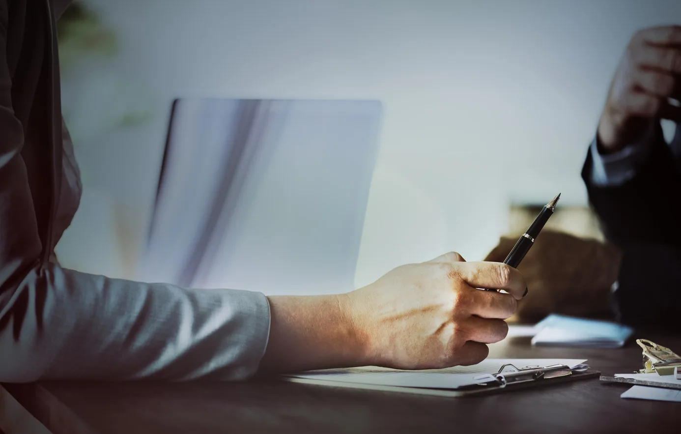 A person writing notes beside an open book