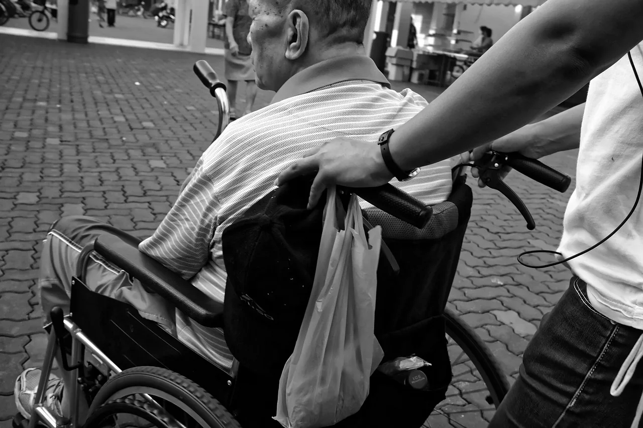 A person holding the handle of a wheelchair