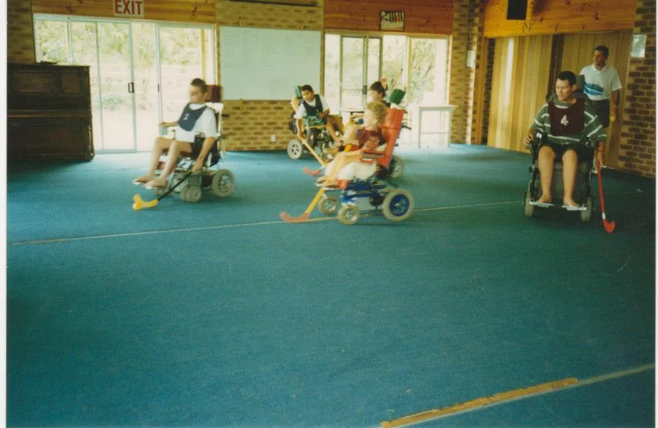 Young wheelchair users taking part in a sports demonstration in a hall