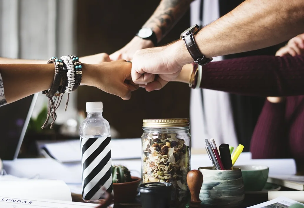 Several people bringing their hands together over a table