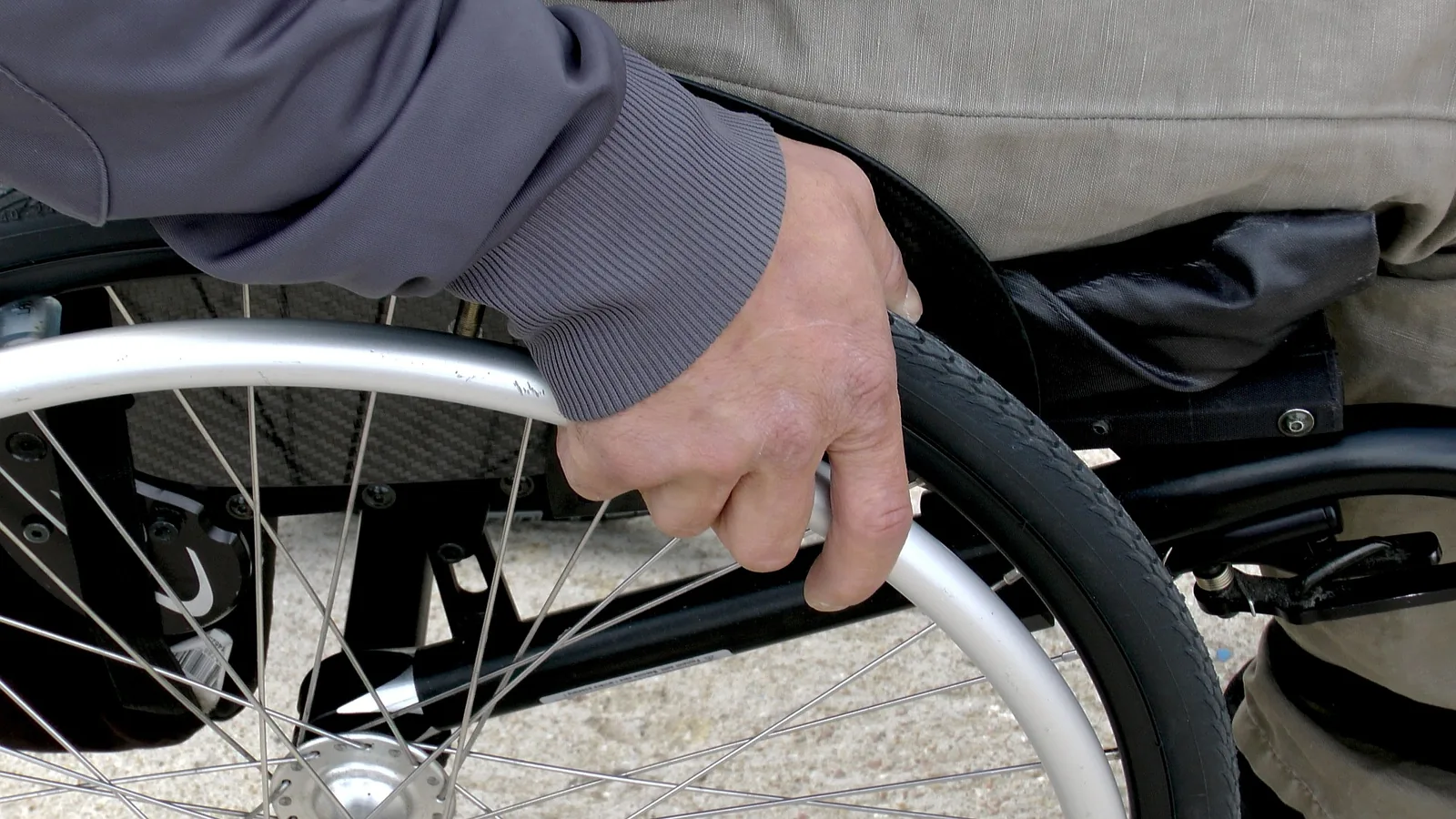 Close-up of a person’s hand on a manual wheelchair wheel
