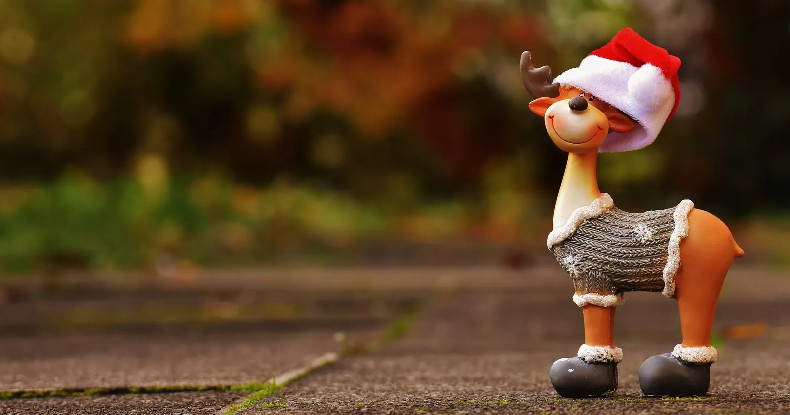 A toy reindeer wearing a Santa hat outdoors