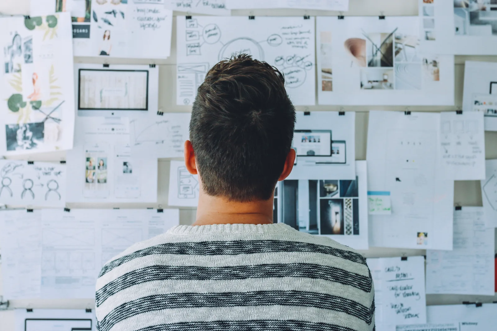 A person facing a wall covered with planning papers
