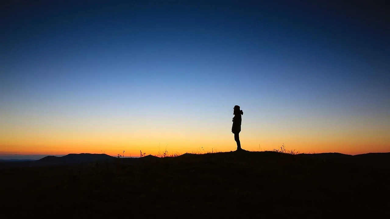 Silhouette of a person standing against a sunset sky