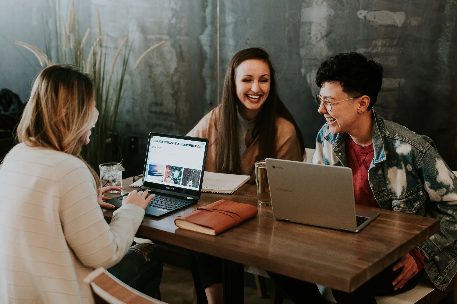 Three people talking around a table with a laptop