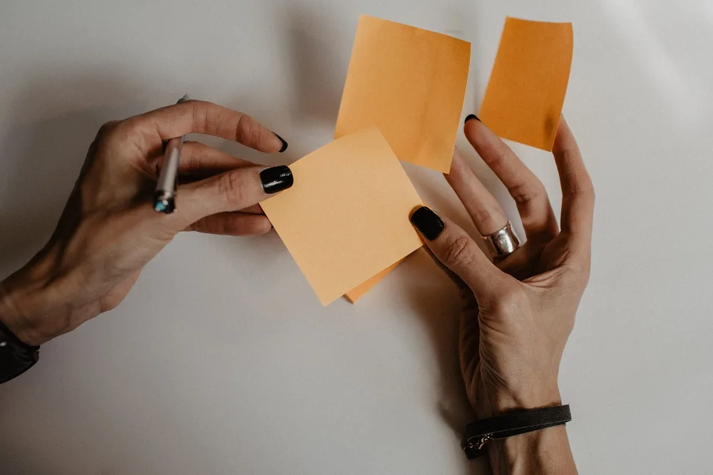Hands holding a pen and paper notes