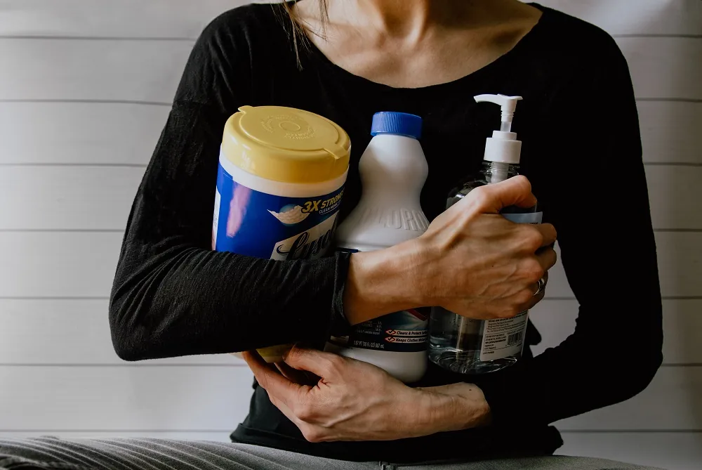 A person holding several cleaning products