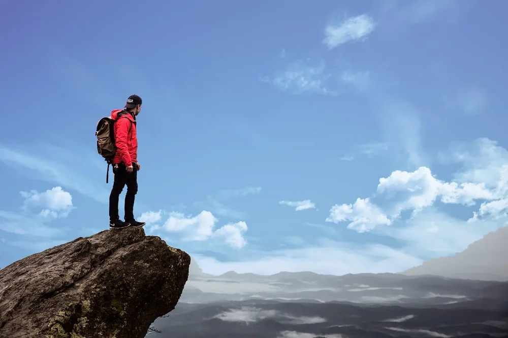 A person with a backpack standing on a rocky peak