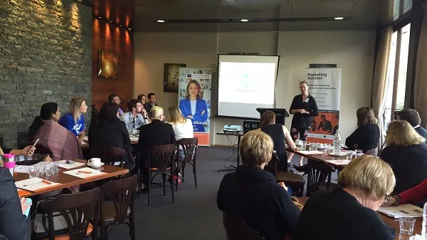 People seated at tables facing speakers in a workshop