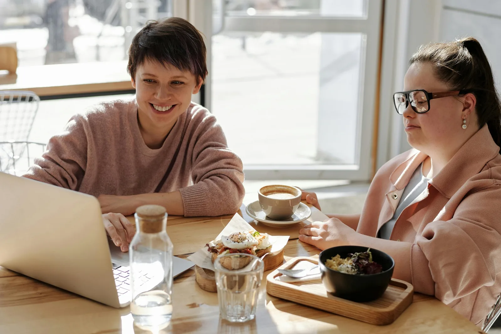 Two people talking at a table with documents and refreshments