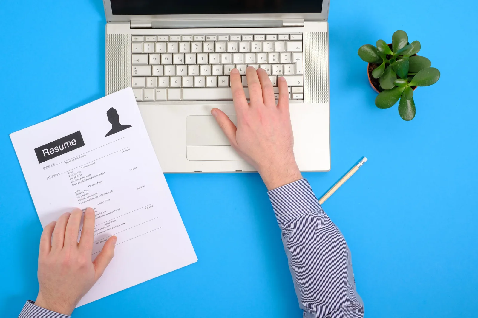 A person using a laptop beside a printed job application