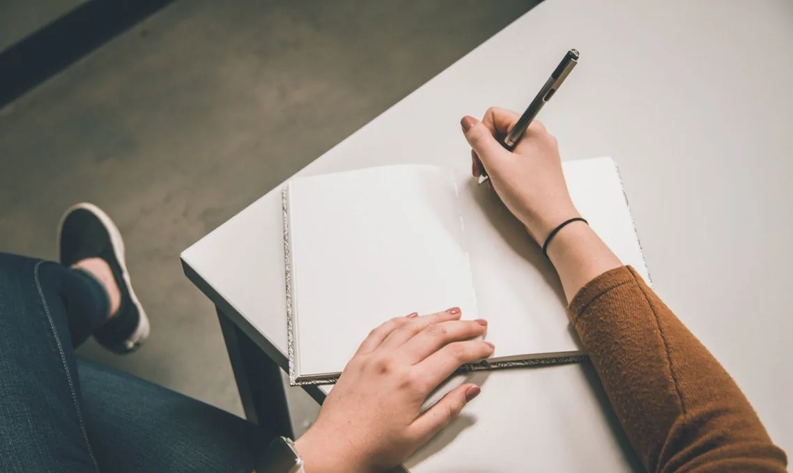 A person writing in an open notebook