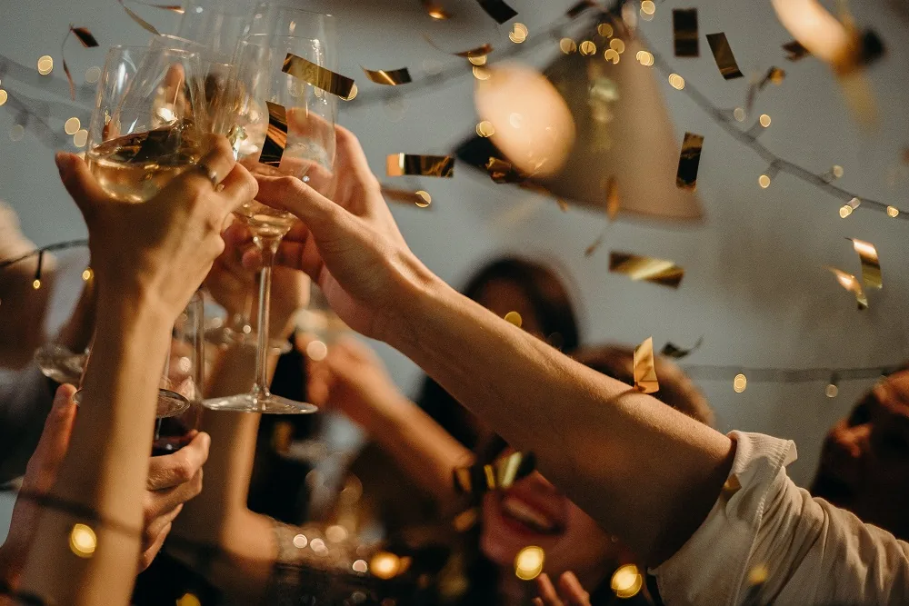 People raising glasses with confetti falling