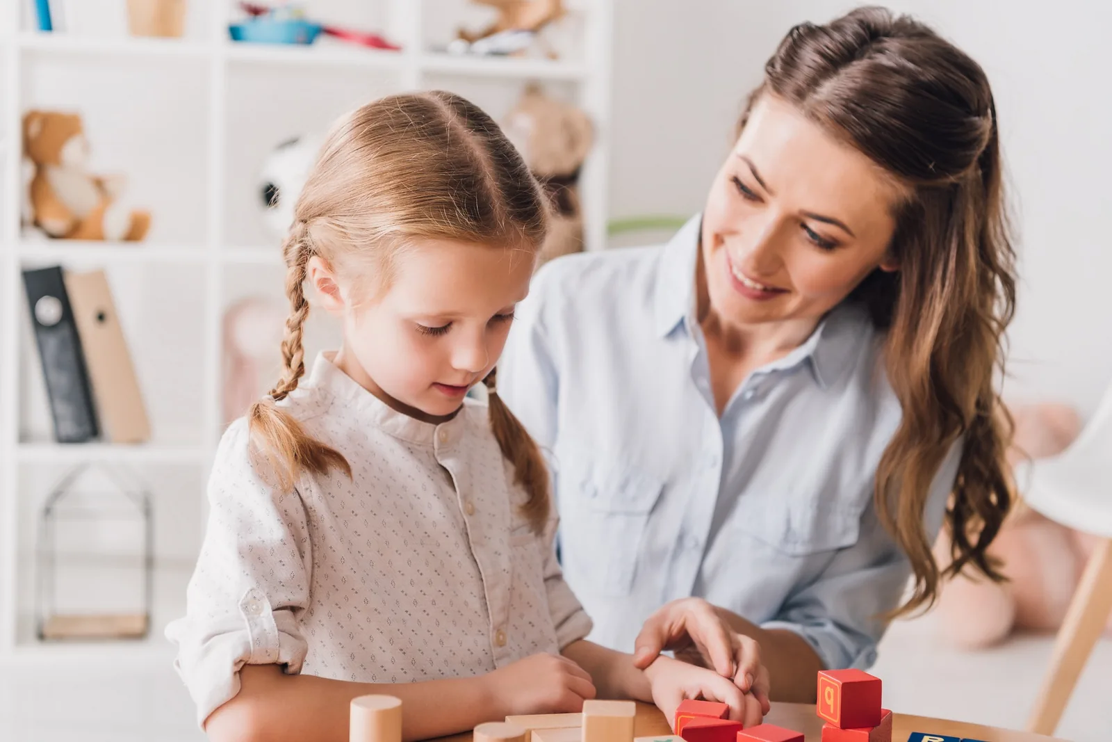 An adult and child working together with blocks at a table
