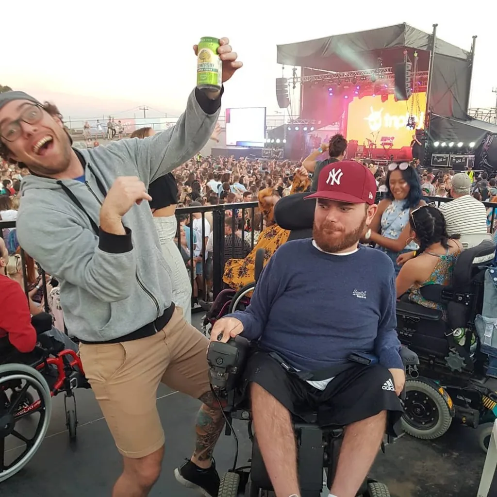 Tristram and his carer on a viewing platform at Ability Fest. Carer is pulling a crazy face.