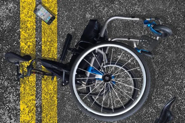 An empty manual wheelchair beside yellow road markings