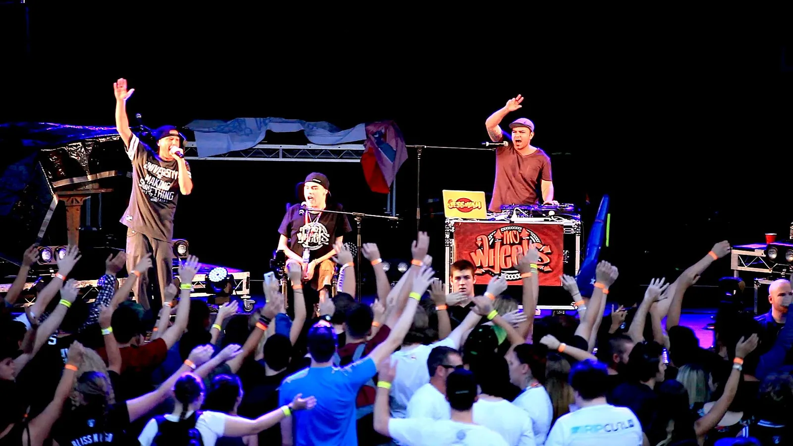 Performers on stage with an audience raising their hands