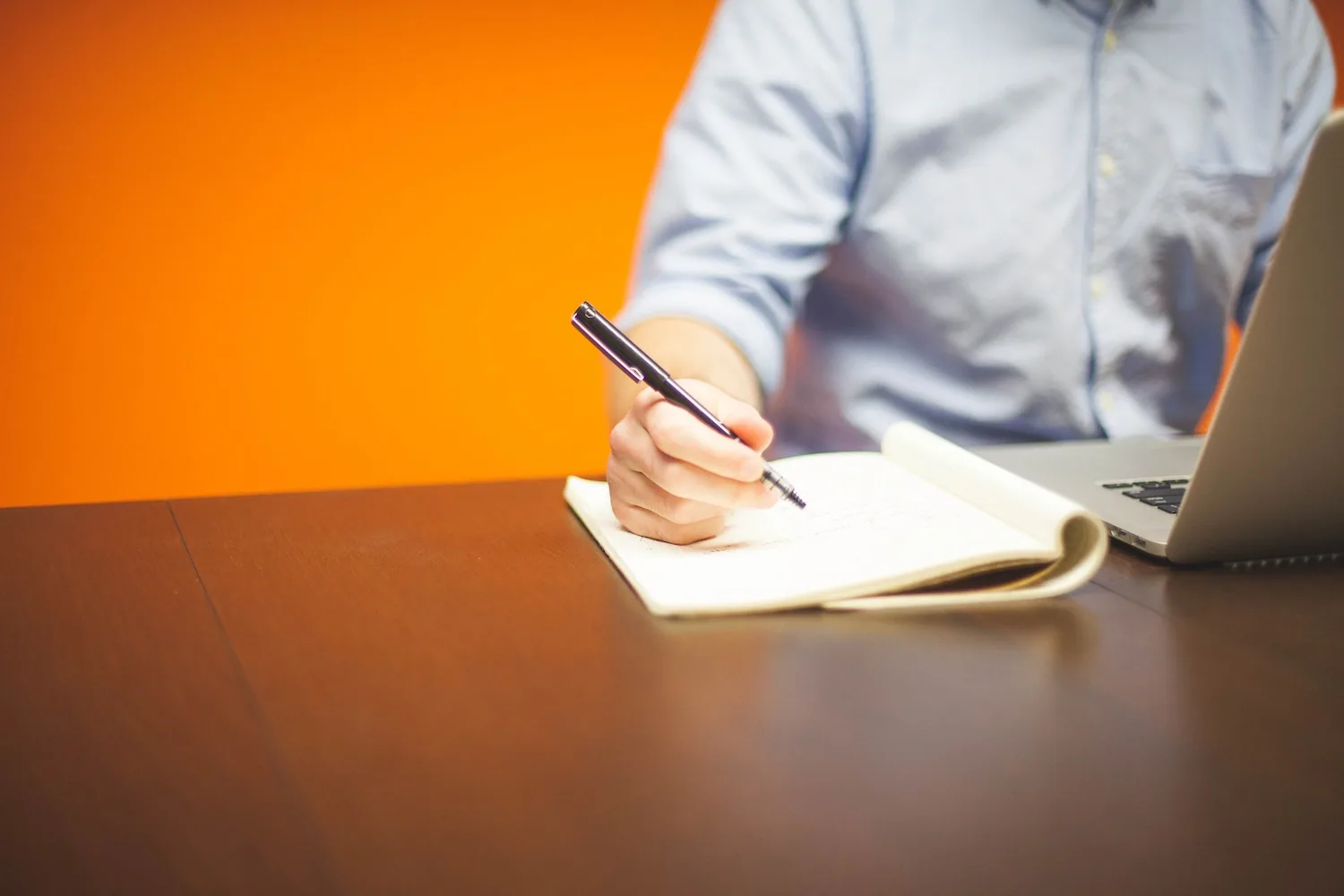 A person writing in a notebook at a table