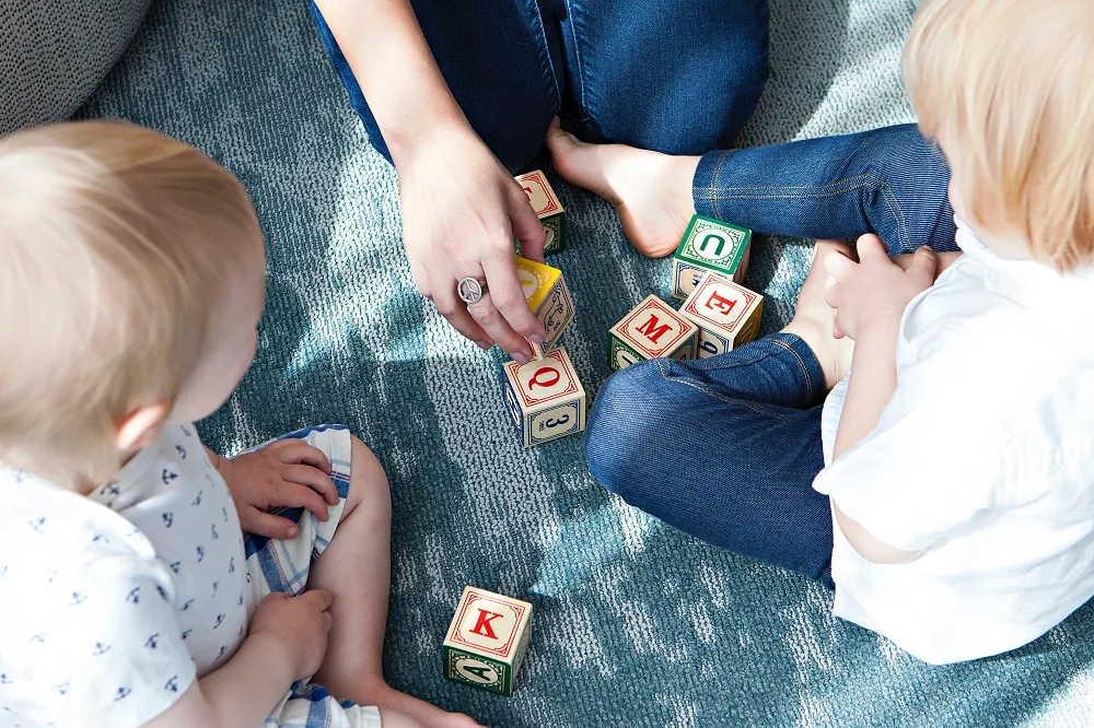 Children playing with letter blocks on a rug