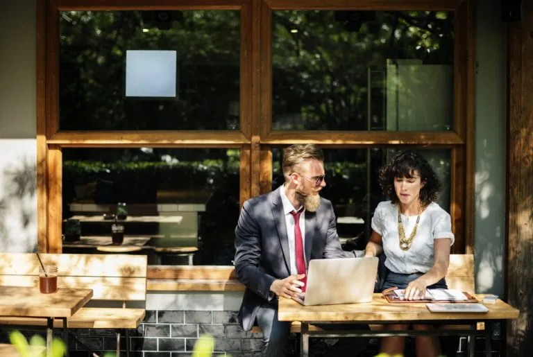 Two business people seated outdoors at a cafe.