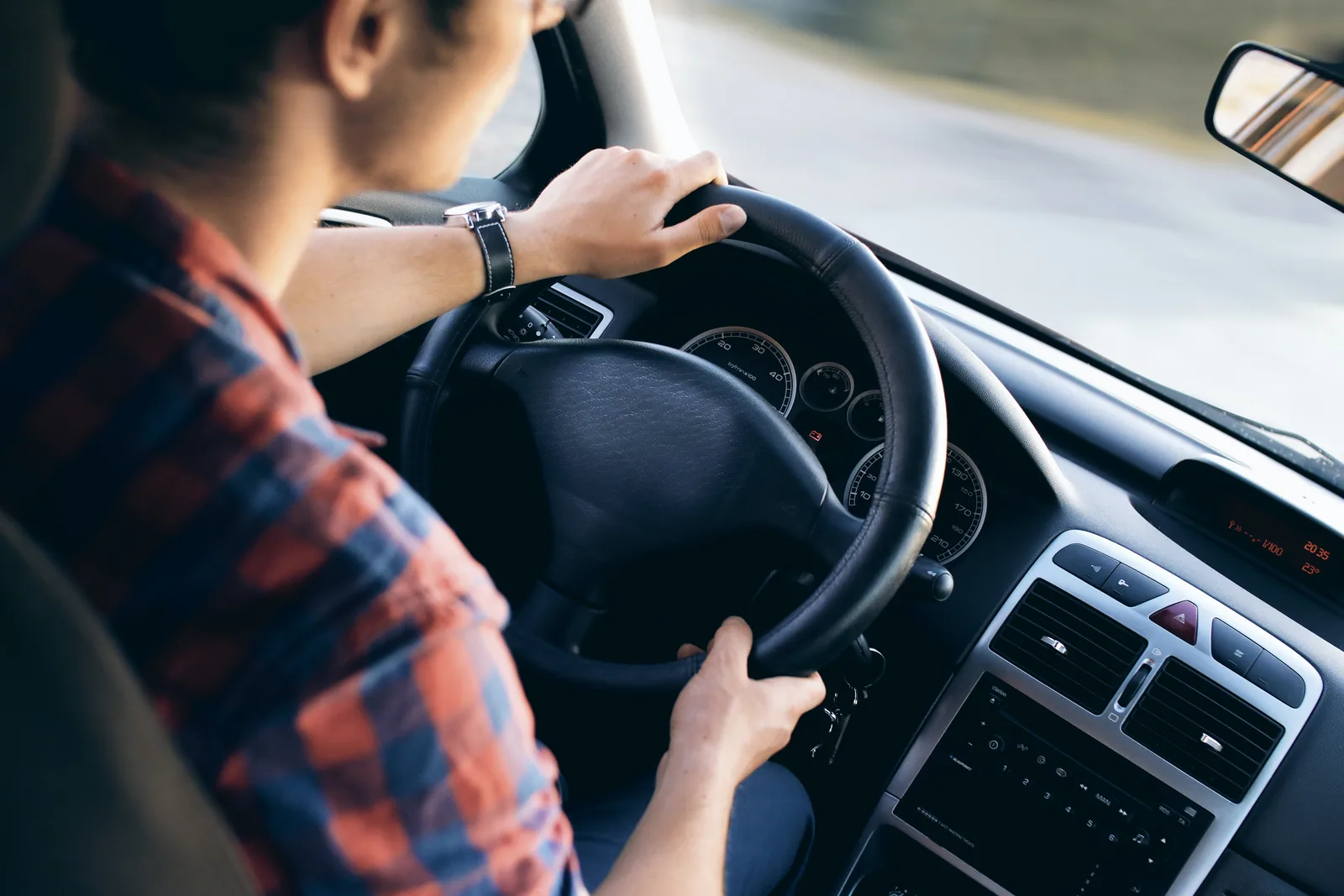 A driver holding the steering wheel inside a vehicle