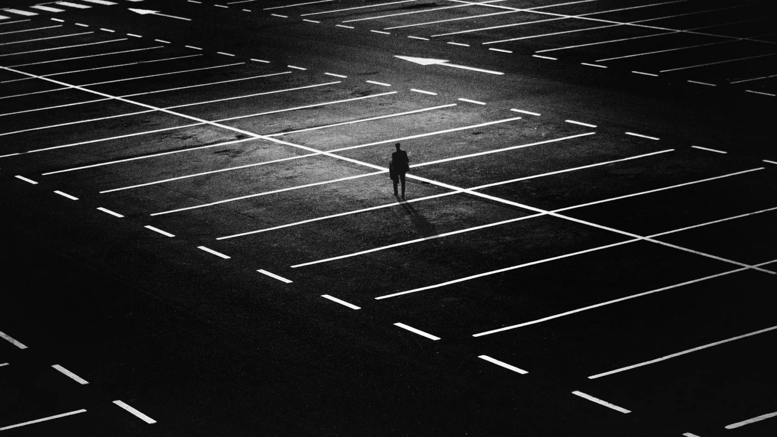 A person walking across a marked parking area