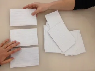 Hands arranging blank paper cards on a desk
