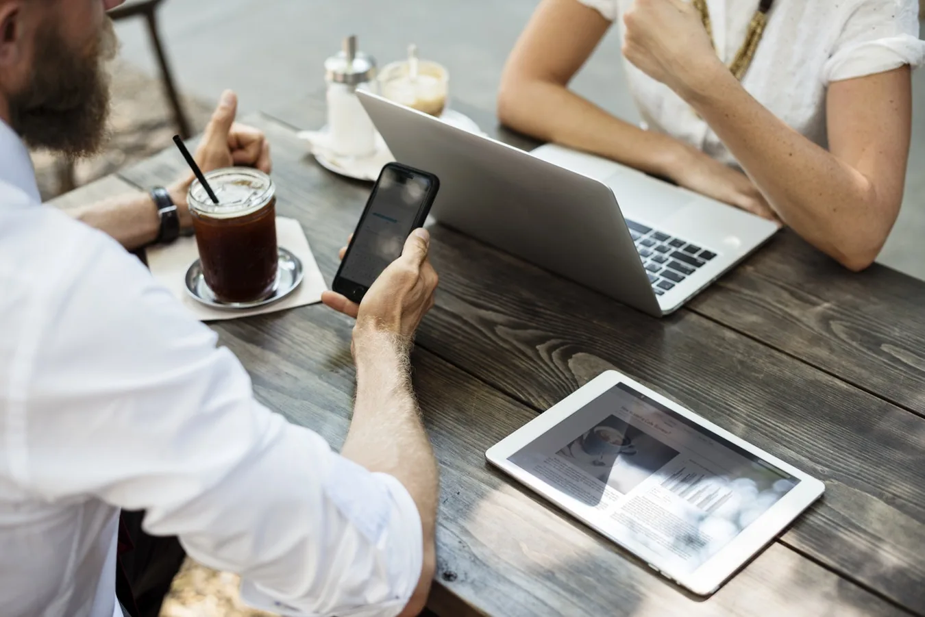 People discussing information with a tablet and laptop at a table