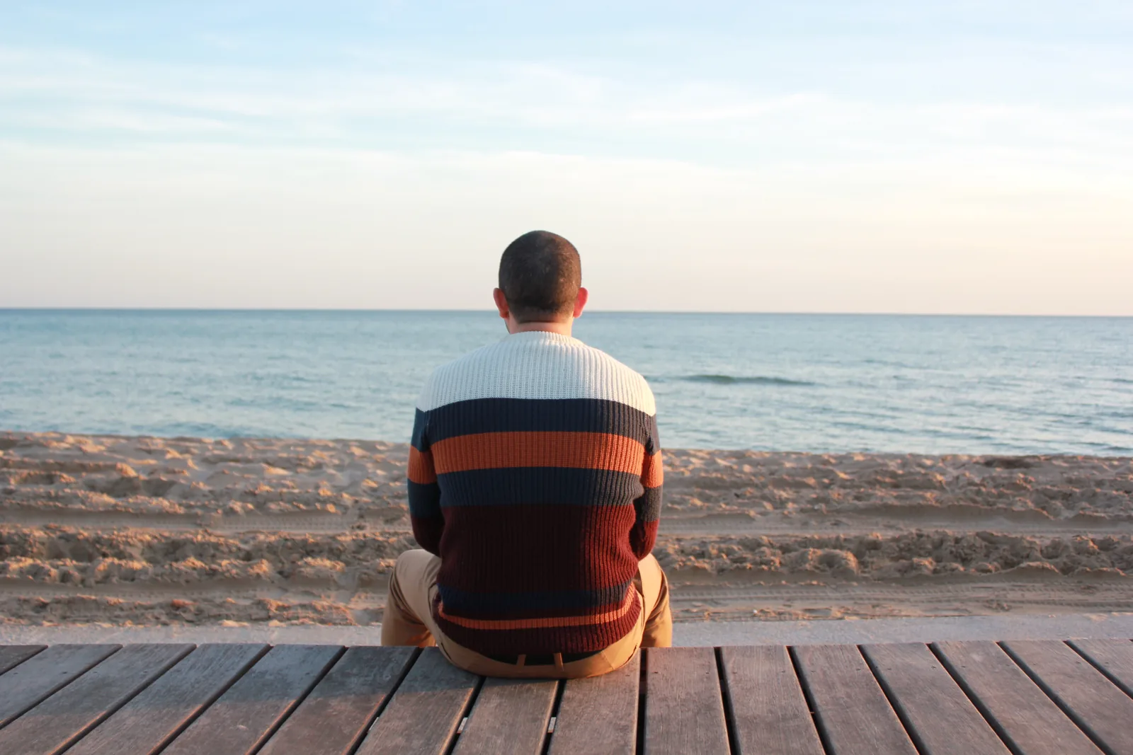 A person sitting alone looking towards the sea