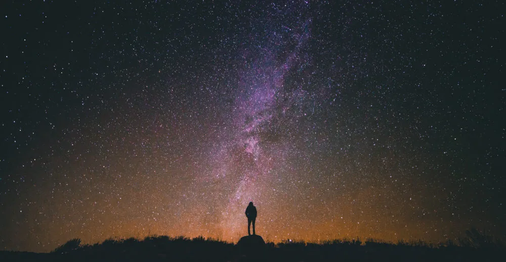 A silhouetted person beneath a star-filled sky