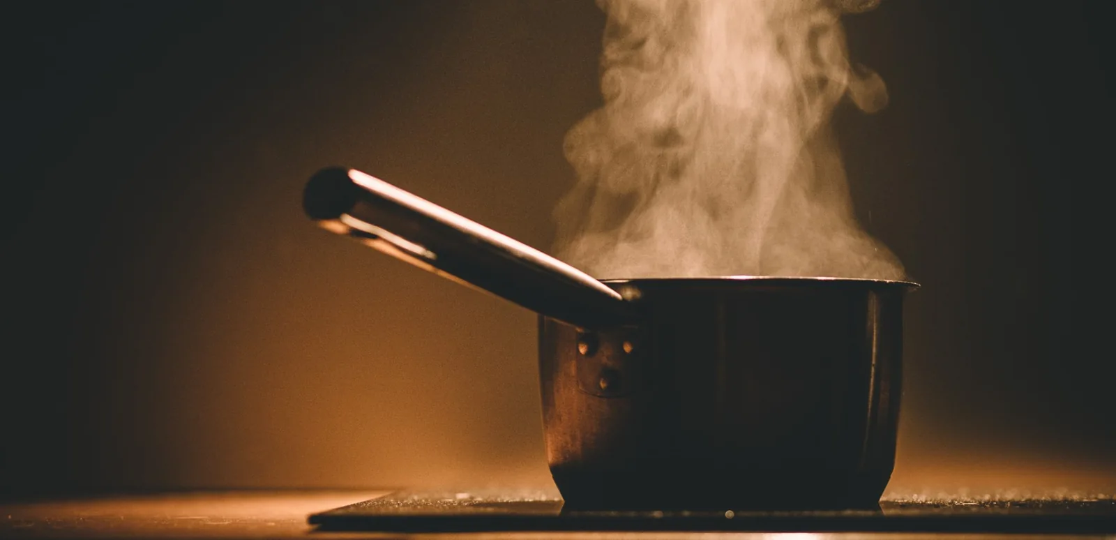 A saucepan with a utensil and rising steam