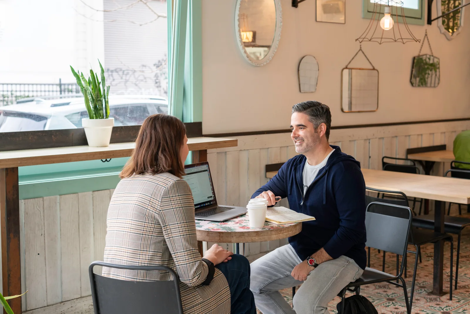 Two people talking across a cafe table