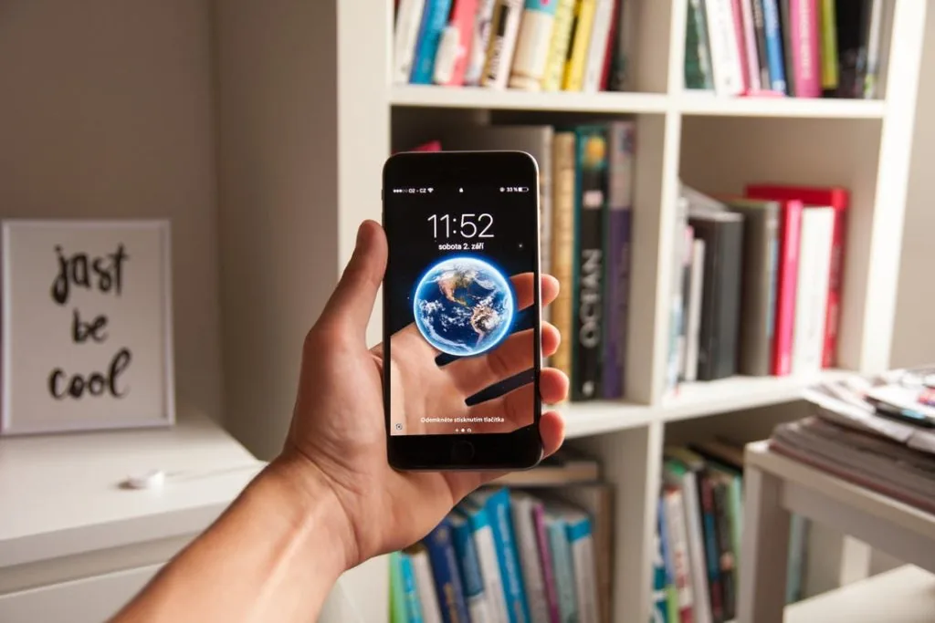 A person holding their phone so that the screen is visible, showing a picture of the world.