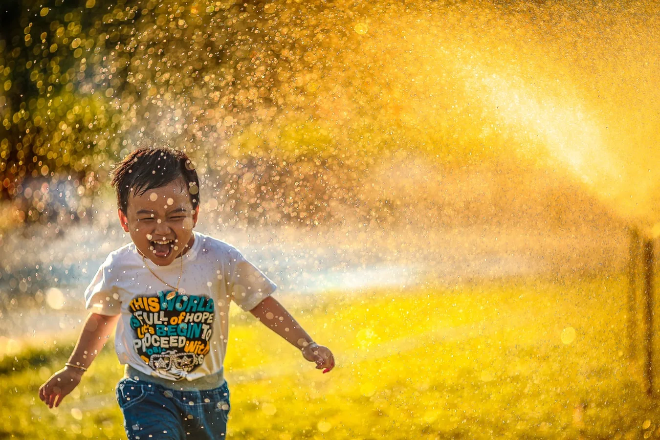 A child playing beneath a spray of water outdoors