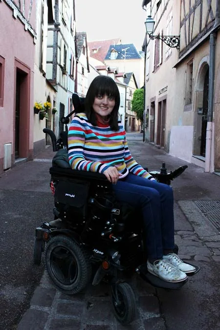 Stacey in her new wheelchair overseas, looking towards the camera.