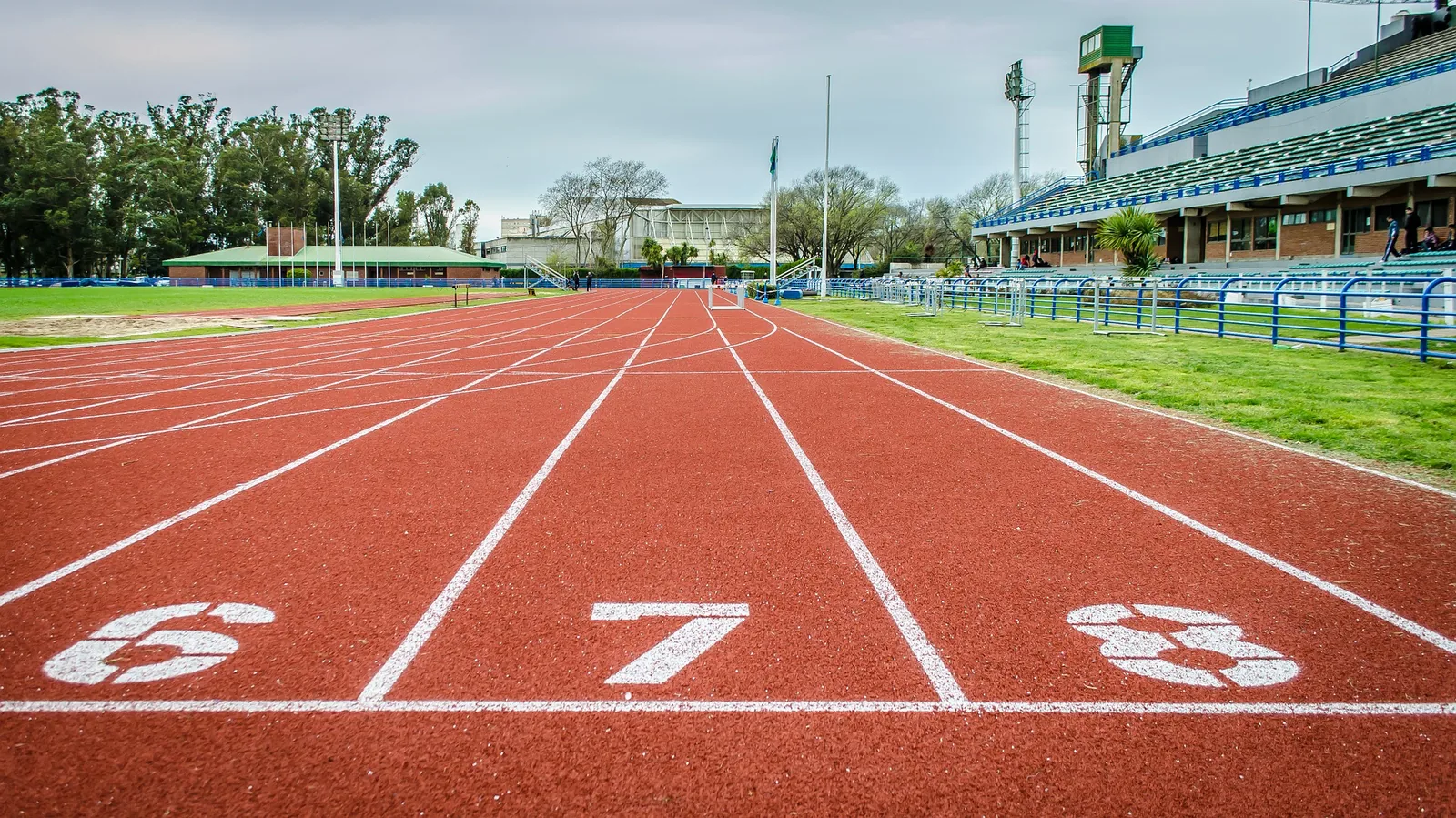 A red athletics track with a stadium in the background