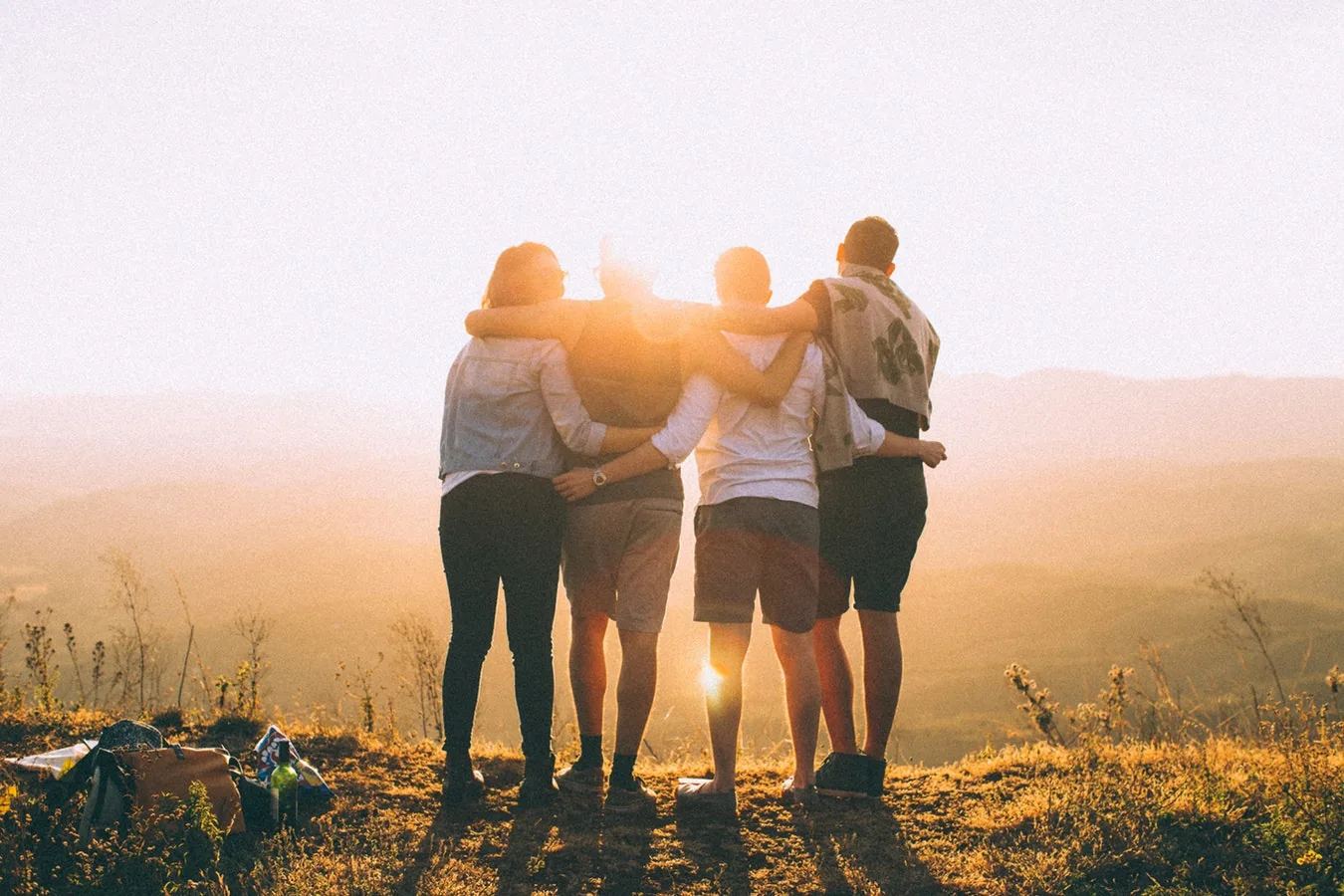 Four people standing together outdoors at sunset