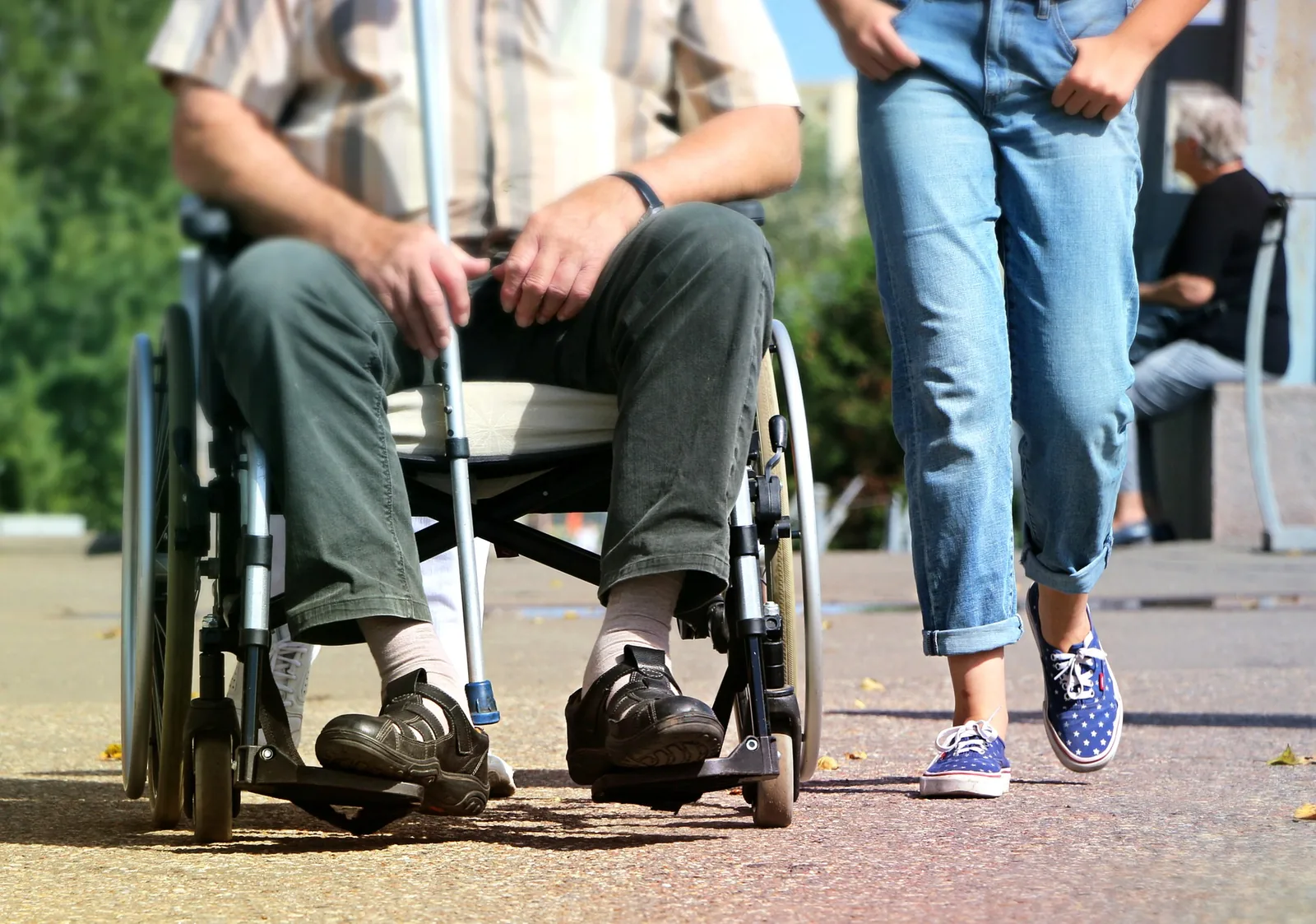 A wheelchair user beside another person outdoors
