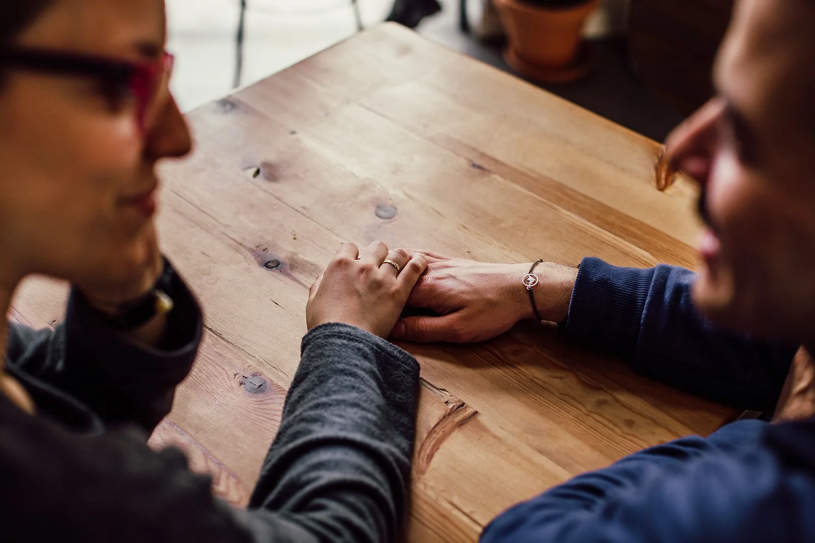 Two people talking across a wooden table