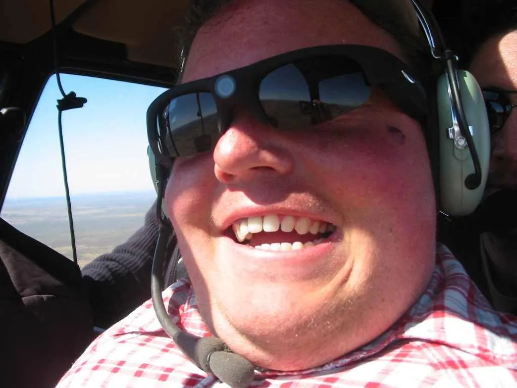 Close-up of a smiling man wearing sunglasses and a headset