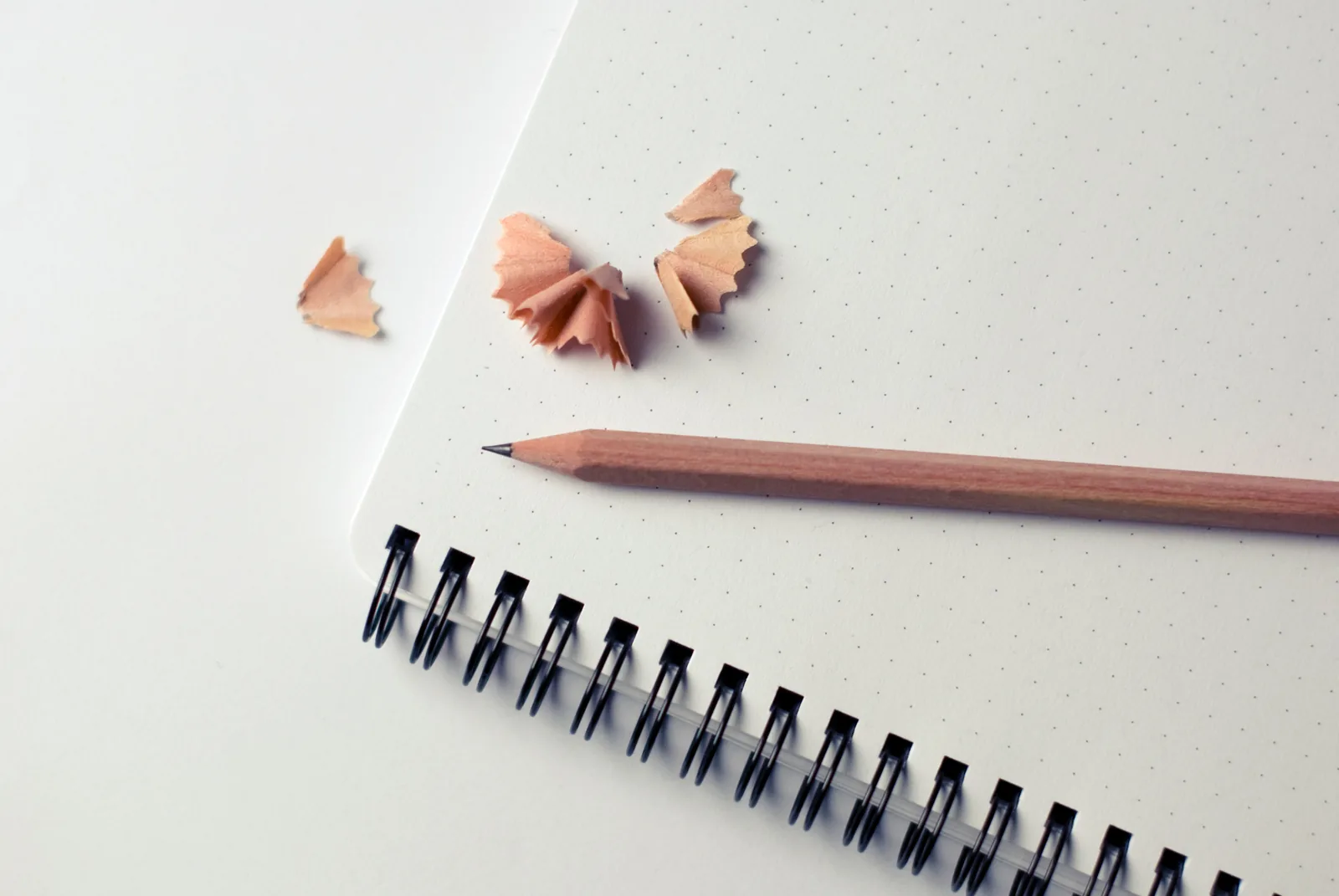 A pencil and shavings beside a spiral notebook
