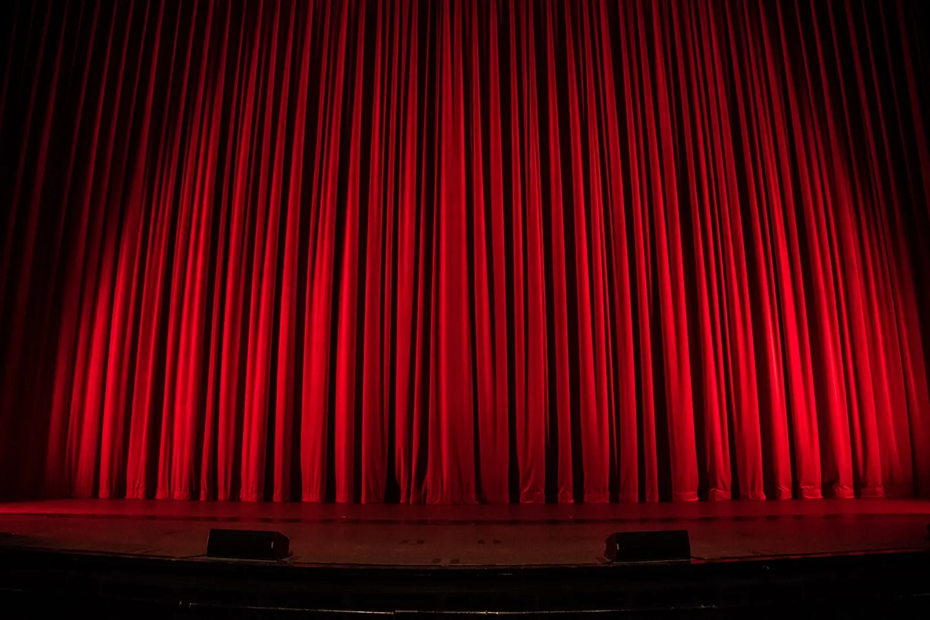 Red curtains drawn across a theatre stage