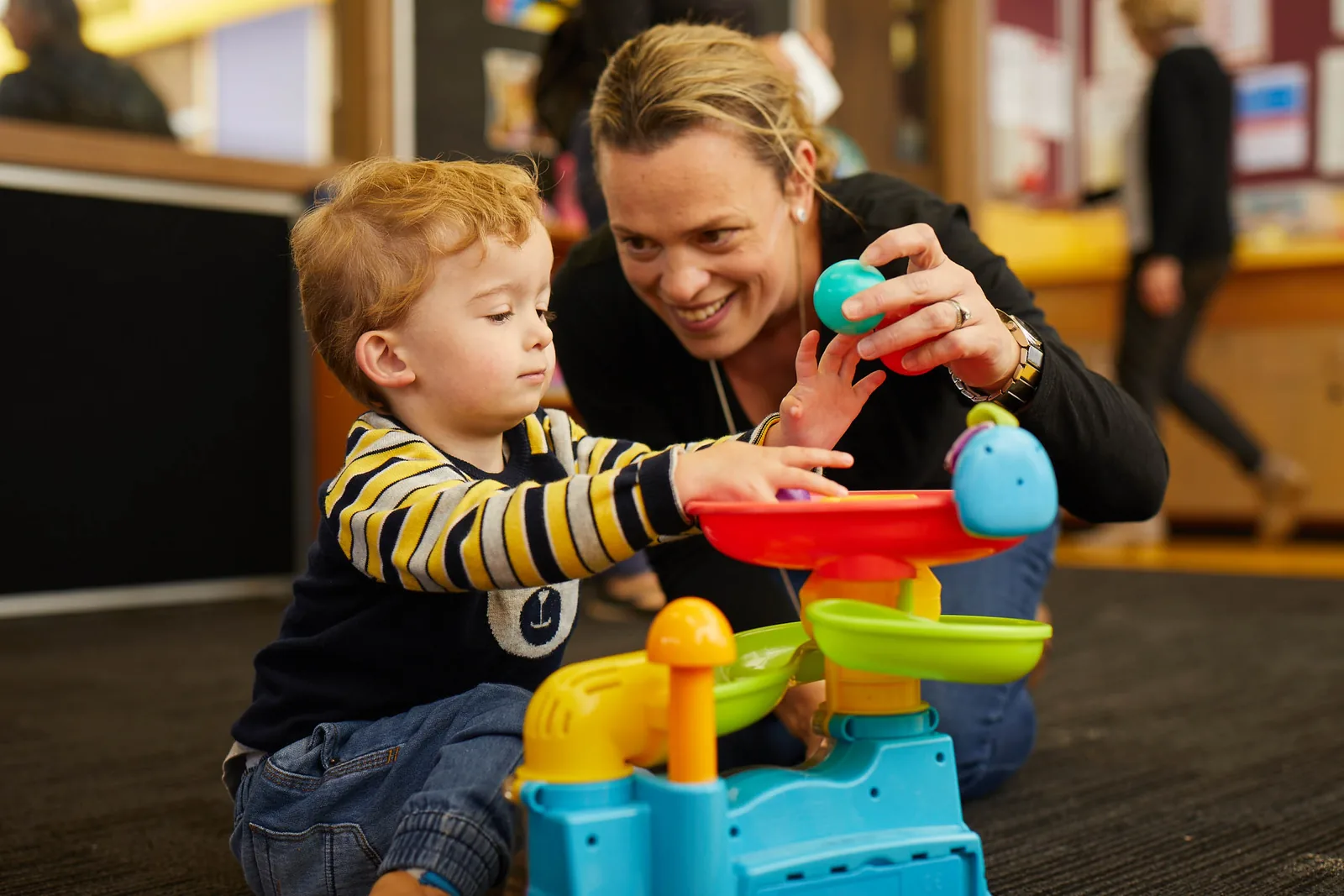 An adult and child playing together with a colourful toy