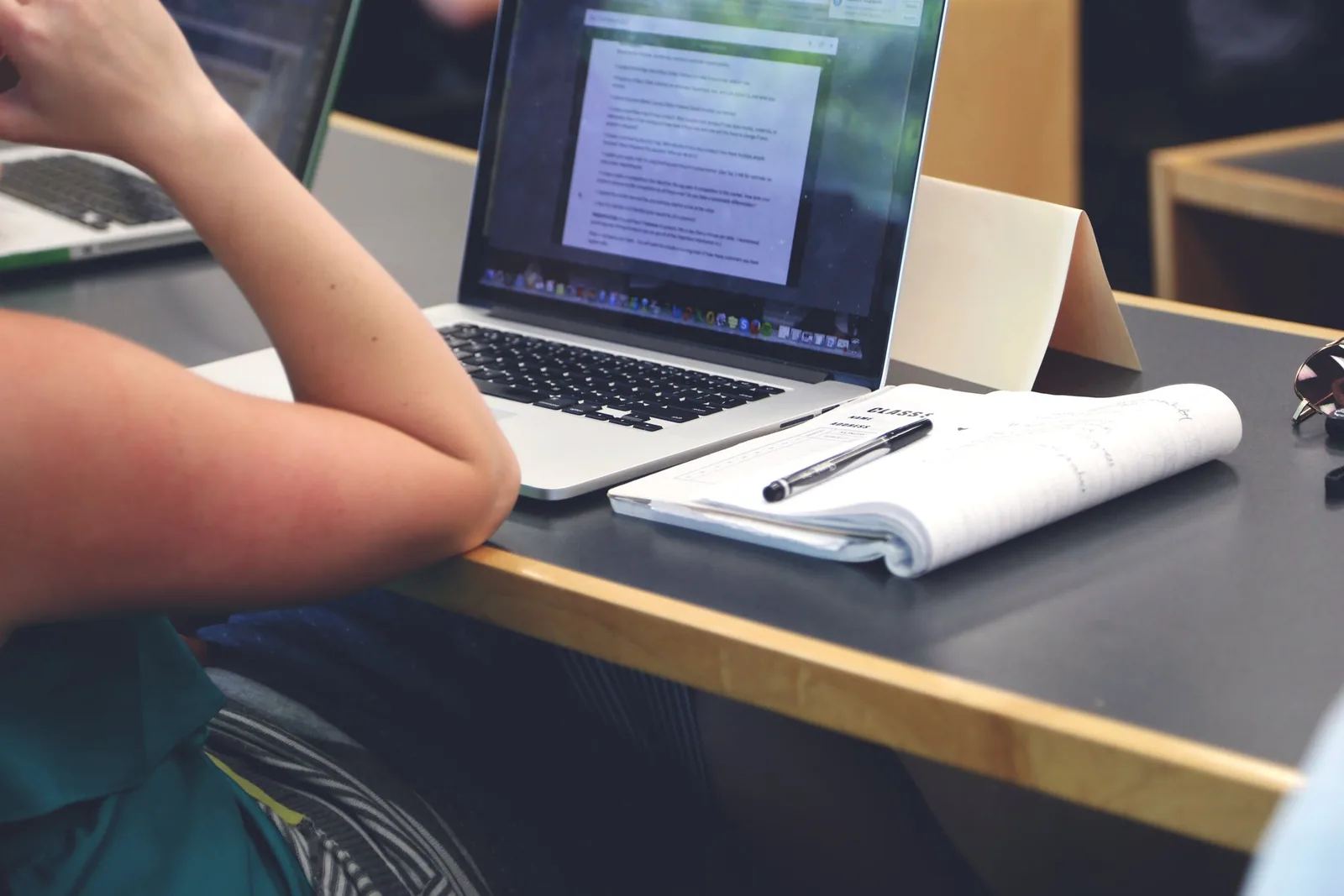 A person working with a laptop and notebook at a desk