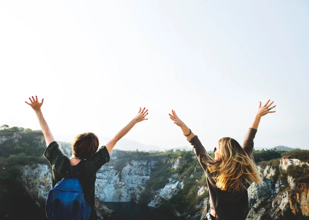 Two people outdoors with their arms raised