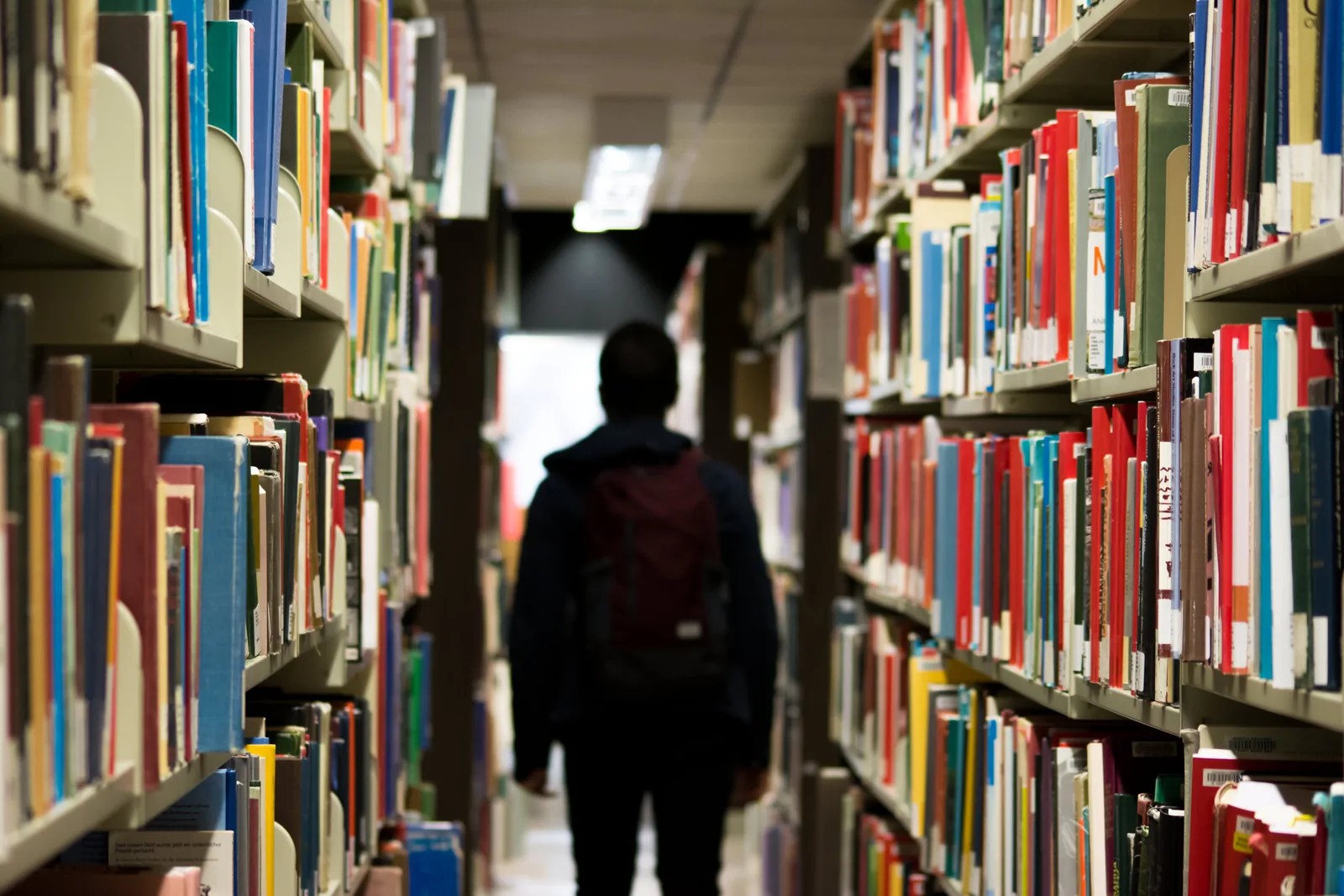 A person walking between library bookshelves