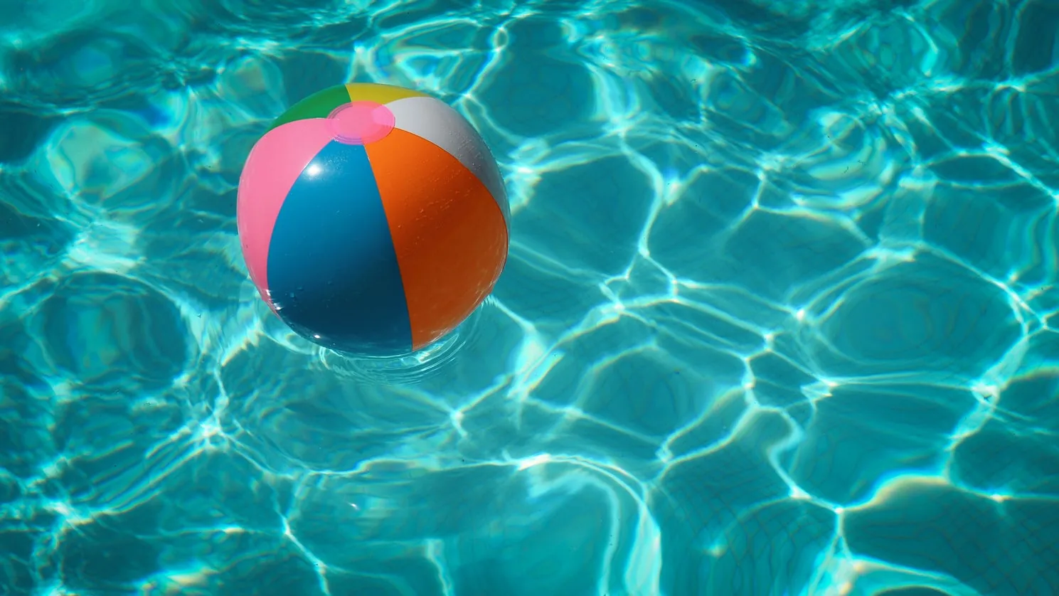 A colourful beach ball floating in a swimming pool