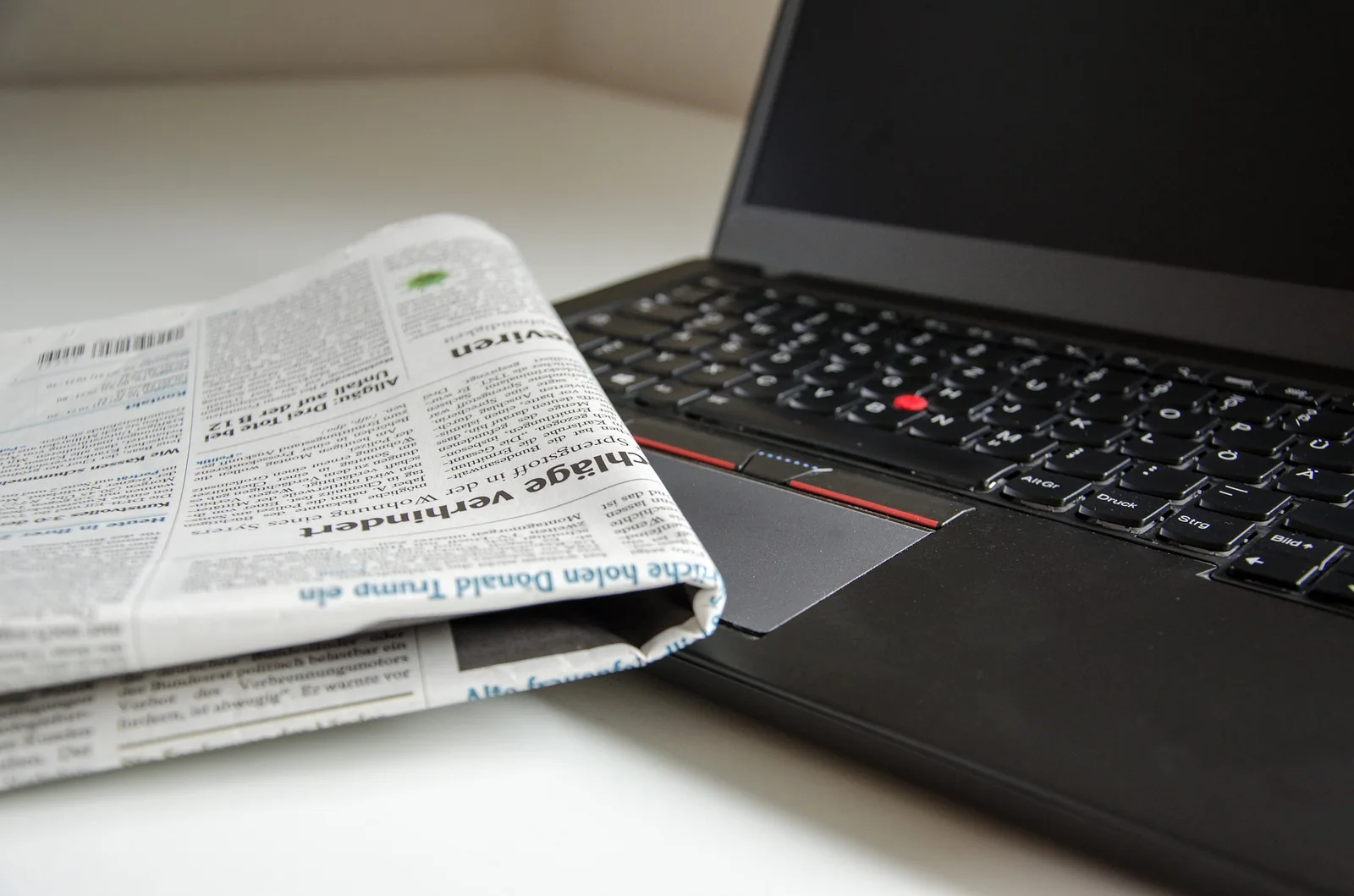 A newspaper beside an open laptop