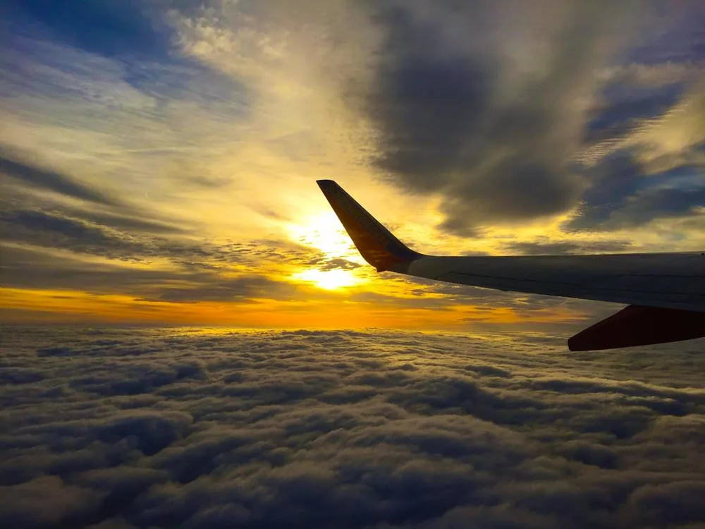 View of an aircraft wing above clouds at sunset