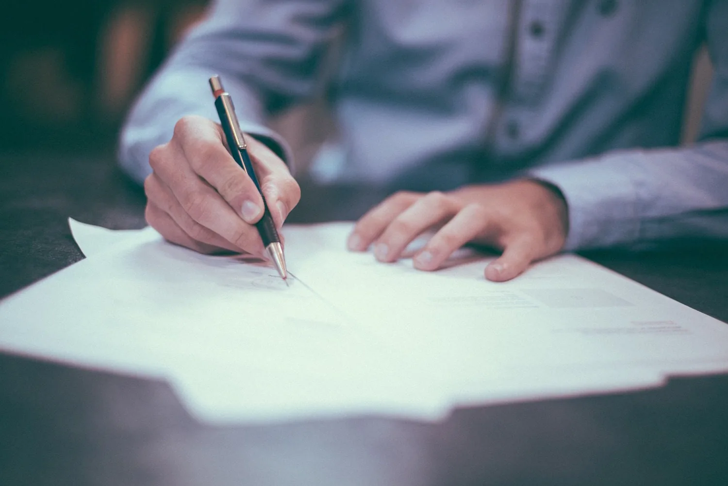 A person writing on documents at a table